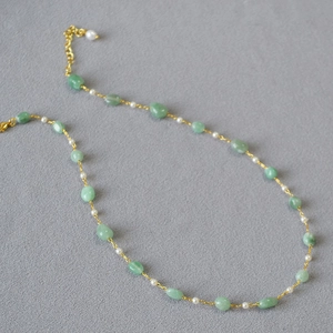 Detail of green natural stones and imitation pearls beaded necklace with gold lobster clasp