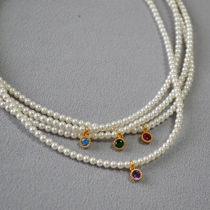 Detailed macro shot of a four-layer pearl necklace with colorful gemstone pendants