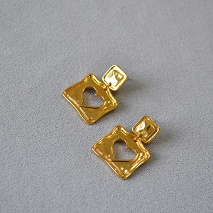 Detail of vintage square earrings with heart cutouts and a hammered gold texture