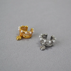 Detail of layered gold and silver ear cuffs with pearls, zircon, and heart pendant