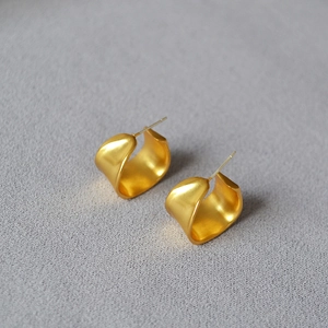 Macro shot of irregular matte gold C-shape wave earrings with 925 silver needles