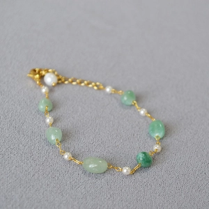 Detail of handmade beaded necklace with green natural stones and white pearls