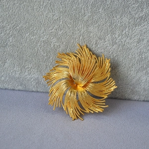 Macro shot of vintage style gold-plated brass brooch with radiant fireworks design