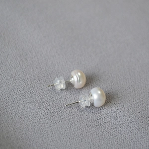 Detailed view of freshwater pearl studs with silver pins and silicone backings on fabric