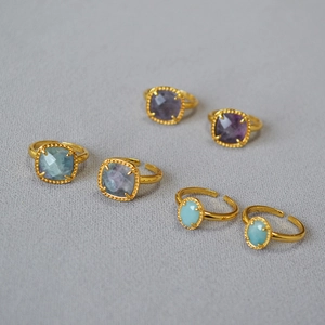 Detail view of six gold-plated adjustable rings with colorful faceted fluorite gemstones