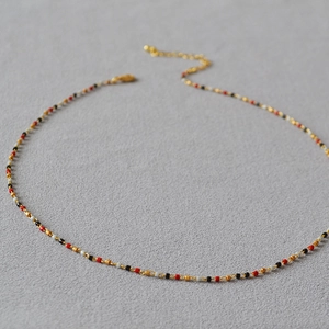 Detail einer handgefertigten Perlenkette mit roten Goldperlen und verstellbarem Verschluss