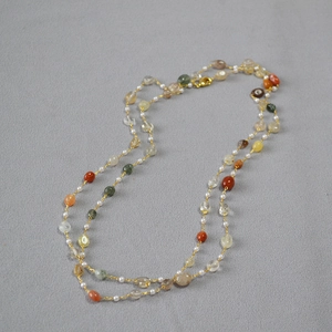 Detail of layered necklace with natural stone beads, white pearls, and gold-tone chain