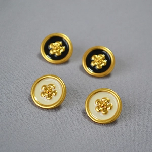 Detail of vintage French camellia earrings in black and cream enamel with gold plating