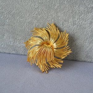 Detail of vintage gold-plated brass brooch with intricate spiral textured metal work