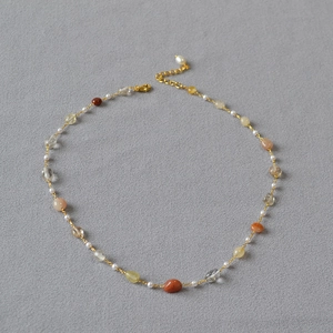 Close-up of handmade beaded necklace with natural stones, pearls and gold chain extension