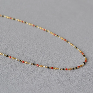 Detailaufnahme der feinen Goldkette mit roten, schwarzen und weißen Mini-Perlen-Akzenten