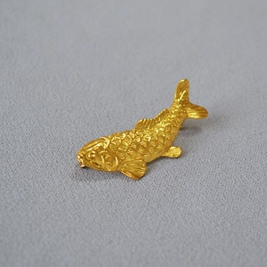 Macro detail of golden koi fish brooch showing intricate scale texture and craftsmanship
