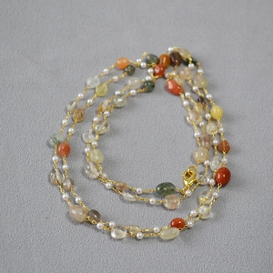Detail of bohemian necklace with natural colorful stones and white freshwater pearls
