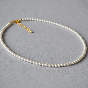 Detail einer eleganten Perlenkette mit goldenem Karabinerverschluss und Kette