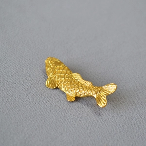 Detailed macro shot of vintage gold-plated koi fish brooch with intricate scale textures