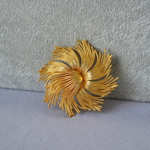 Macro shot of gold vintage flower brooch with intricate spiral textured metal details