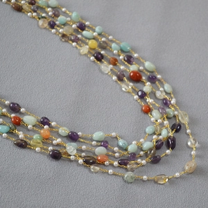 Detail of layered gold necklace with natural amethyst, agate and freshwater pearls
