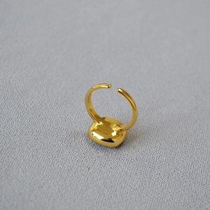 Detail of adjustable gold-plated ring band showing smooth back finish on fabric background