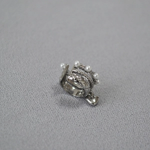 Macro detail of silver ear cuff featuring quilted patterns, pearls and a heart charm