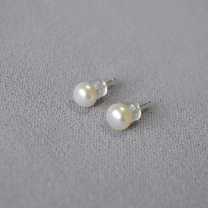 Detail of freshwater pearl earrings with silver needles and clear silicone backs