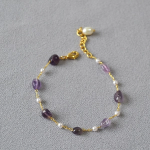 Detail of amethyst beads and white pearls on a gold chain necklace with adjustable clasp