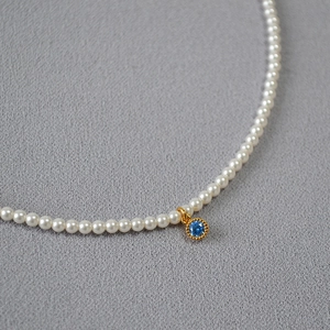 Detailed macro view of high-lustre pearls and a vintage gold pendant with blue zircon stone
