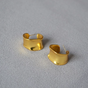 Detailed view of matte gold irregular C-shape hoop earrings with a brushed metal texture