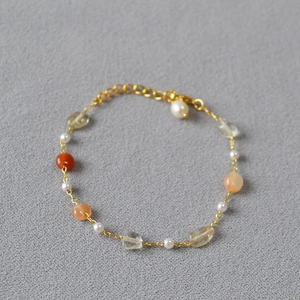 Detail of beaded necklace with pearls, gemstones and gold chain on gray fabric