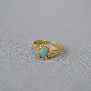 Detail view of adjustable gold-plated ring with oval blue gemstone and beaded edge