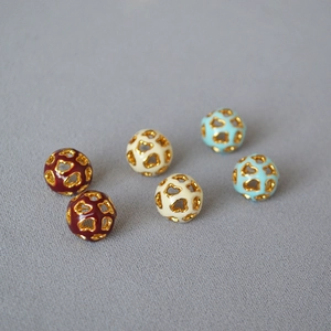 Vue détaillée de boucles d'oreilles sphériques en émail creux aux motifs géométriques
