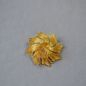 Detail of vintage golden sunburst brooch featuring intricate grainy texture on brass petals