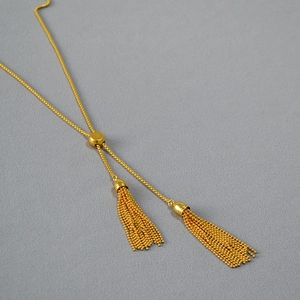 Detail of adjustable gold Y-necklace featuring double metallic bead chain tassels