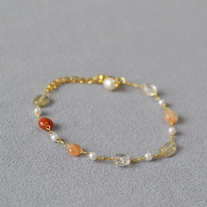 Close-up of gold chain necklace with colorful semi-precious stones and small white pearls