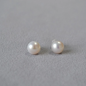 Elegant 925 sterling silver freshwater pearl stud earrings on minimalist fabric background
