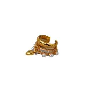 Quilted gold ear cuff with zircons, white pearls and a heart pendant on white background