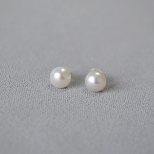 Detail view of 925 silver stud earrings with natural freshwater pearls on gray fabric