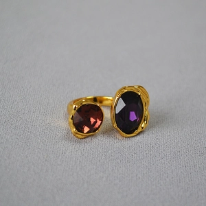 Dettaglio di anello dorato vintage con pietre preziose viola e marrone scuro