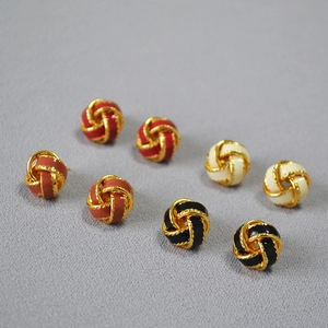 Détail macro de boucles d'oreilles nœuds en quatre couleurs avec bordure dorée torsadée