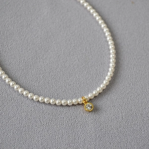 Detailed close-up of a high-luster pearl necklace with a gold-plated cubic zirconia pendant