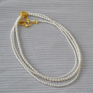 Detailansicht der dreilagigen weißen Perlenkette mit verstellbarem goldenem Karabiner