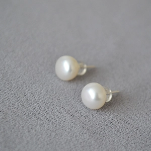 Detail of 925 silver stud earrings with white freshwater pearls on grey fabric