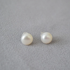 Macro shot of 925 silver pearl stud earrings with soft white luster and silicone backs