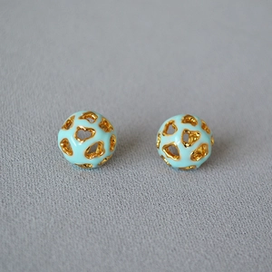 Vue macro de boucles d'oreilles sphériques ajourées avec émail bleu et cœurs dorés