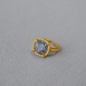 Macro shot of square faceted multi-color fluorite gemstone with vintage gold rope texture