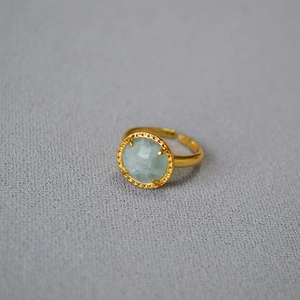 Detailed shot of gold-plated brass ring featuring faceted light blue natural gemstone