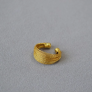 Détail d'une bague multicouche en laiton plaqué or avec un design perlé tressé