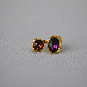 Dettaglio dell'anello dorato regolabile con pietre preziose rosse e viola