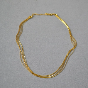 Detail of layered gold fine chain necklace with lobster clasp and adjustable extension link