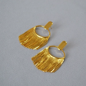 Vue détaillée de boucles d'oreilles dorées à franges avec texture métallique polie