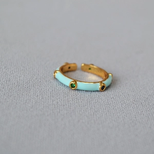 Bamboo style gold open ring with mint enamel and colorful zircon stones on grey fabric